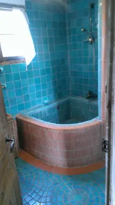 a blue tiled bathroom with a tub with a shower at maison florentine in La Gaude