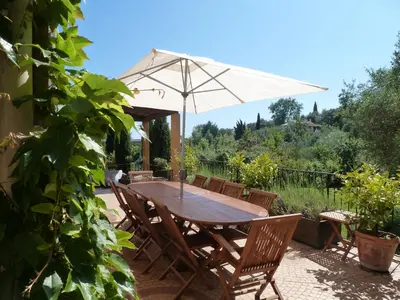 a wooden table and chairs with an umbrella at maison florentine in La Gaude
