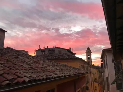 a sunset over the roofs of a city with a clock tower at Spacious and bright flat close to the beach : heart of old Nice in Nice