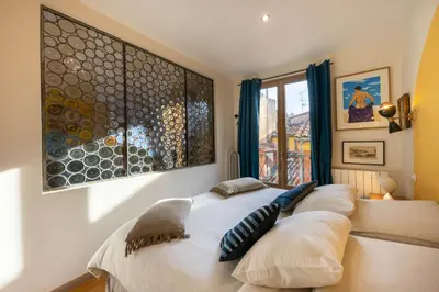 a bed in a room with a large painting on the wall at Spacious and bright flat close to the beach : heart of old Nice in Nice