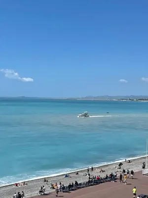 a group of people on a beach with a boat in the water at OPERA PROMENADE 2 Renovated 1 min to Beach Air Conditioning in Nice