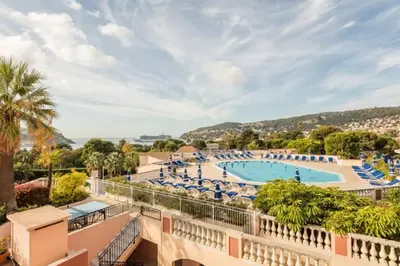 a resort with a large swimming pool with blue chairs at Casa Alessia - Villefranche-sur-mer in Villefranche-sur-Mer