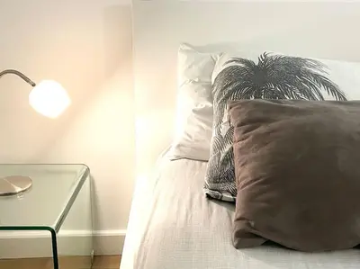 a bed with a pillow and a table with a lamp at Homelivia, VIEUX NICE, appartement de charme, clim balcon in Nice
