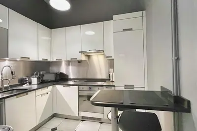 a kitchen with white cabinets and a table in it at Homelivia, VIEUX NICE, appartement de charme, clim balcon in Nice