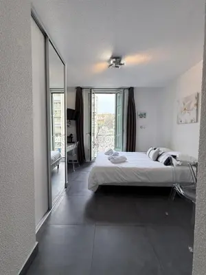 a bedroom with a bed and a large window at Studio central avec balcon- Plage - Tram - Aéroport in Nice