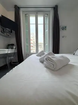 a white bed with towels on it with a window at Studio central avec balcon- Plage - Tram - Aéroport in Nice