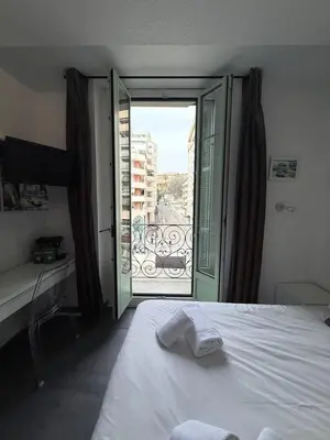 a bedroom with a bed and a door to a balcony at Studio central avec balcon- Plage - Tram - Aéroport in Nice