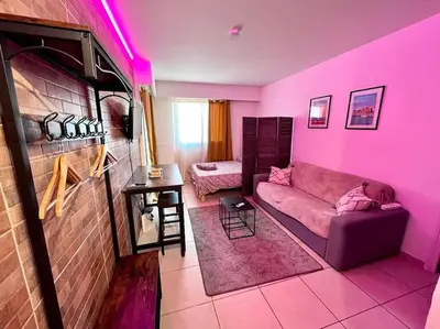 a living room with a couch and a pink wall at Parking + piscine, tout confort, proche aéroport & mer in Saint-Laurent-du-Var