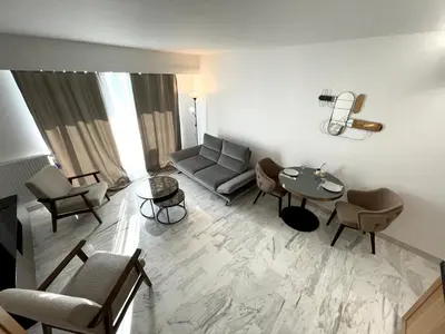 a living room with a couch and a table and chairs at Appartement bord de mer avec piscine in Saint-Laurent-du-Var
