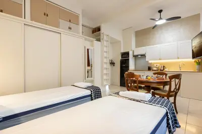 two beds in a room with a table and a kitchen at La plume de Paul in Nice