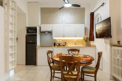 a kitchen with a wooden table and chairs in a room at La plume de Paul in Nice