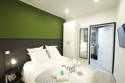a bedroom with a large white bed with a green wall at 06R - Nice modern apartment - Vieux Nice in Nice