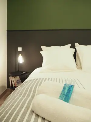 a white bed with a green headboard and white pillows at 06R - Nice modern apartment - Vieux Nice in Nice
