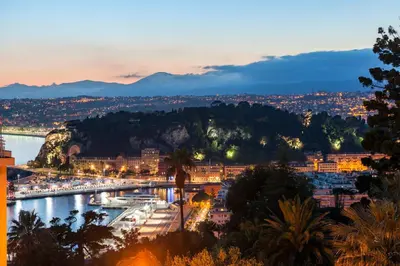 a view of a city and a river at night at Ferienwohnung Les Oliviers über den Dächern von Nizza ruhig sonnig Meerblick Pool Tiefgarage Parkplatz in Nice