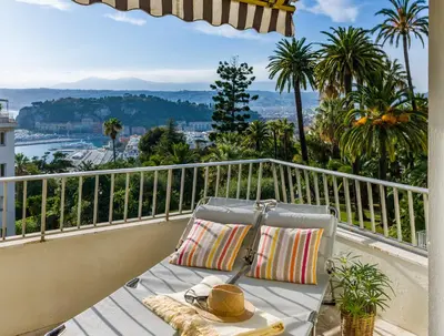 a chair on a balcony with a view of the city at Ferienwohnung Les Oliviers über den Dächern von Nizza ruhig sonnig Meerblick Pool Tiefgarage Parkplatz in Nice