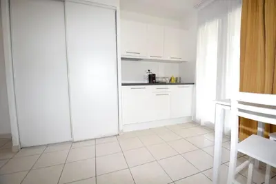 a kitchen with white cabinets and a white tile floor at Palais des Domes Piscine et Parking in Nice