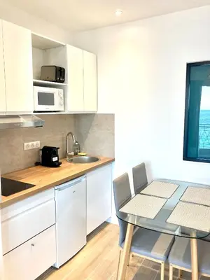 a kitchen with white cabinets and a table and a sink at Residence le Florence in Nice