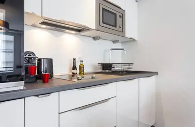 a kitchen with white cabinets and a microwave at Royal apartment near the beaches in Nice