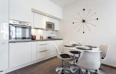 a kitchen with a table and chairs and a clock on the wall at Royal apartment near the beaches in Nice