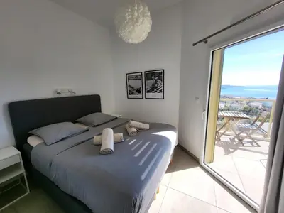 a white bedroom with a bed and a chandelier at Blue Pearl Vue Mer By Avecoeur in Nice