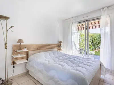 a white bedroom with a large bed and a window at Apartment Le Marbeau-2 by Interhome in Cagnes-sur-Mer