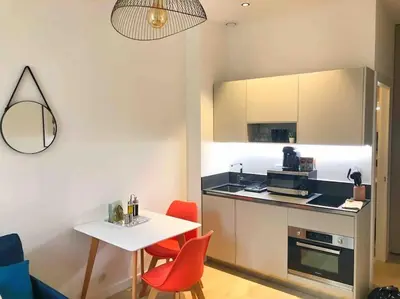 a small kitchen with a white table and red chairs at Homelivia, Votre Appartement ideal pour découvrir Nice in Nice