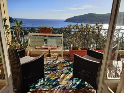a patio with two chairs and a view of the ocean at Vintage flat on Villefranche bay - free car park in Villefranche-sur-Mer
