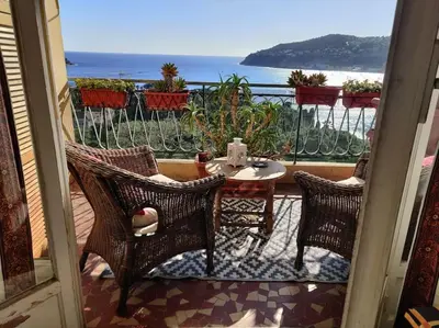 a balcony with a table and chairs and the ocean at Vintage flat on Villefranche bay - free car park in Villefranche-sur-Mer