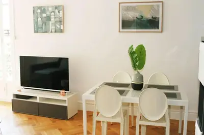 a dining room with a table with chairs and a tv at Central, climatisé, proche Promenade des anglais. in Nice