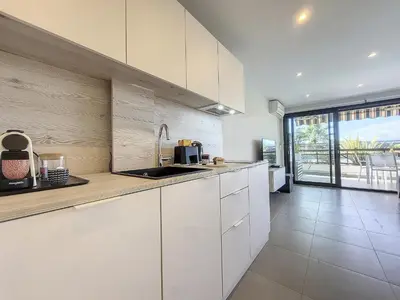 a kitchen with white cabinets and a large window at Nestor&Jeeves - GRAND SUD TERRASSE - Pool - Free parking in Nice