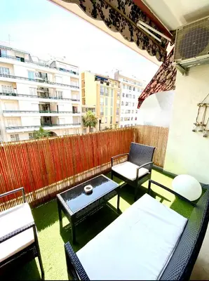 a balcony with chairs and tables and a fence at Cosy Californie in Nice