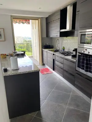 a kitchen with black cabinets and a large window at NICE BAIE DES ANGES in Nice