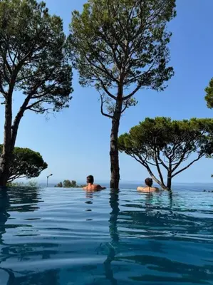 two men are swimming in a pool of water with trees at Balcon sur la Méditerranée in Nice