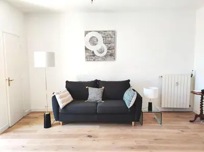 a living room with a black couch in a room at Top floor nest, balcony close to sea and old-town Bail Mobilité in Nice