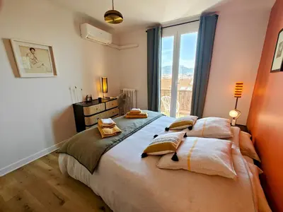 a bedroom with a large bed with a large window at Cozy roof terrace near Promenade des Anglais - AC in Nice