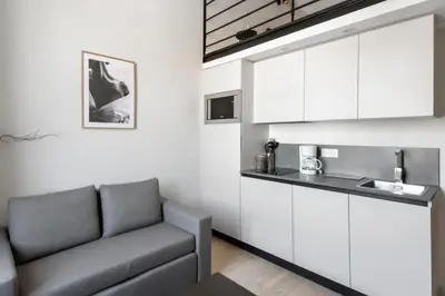 a living room with a couch and a kitchen at Studio Francilia - Welkeys in Nice