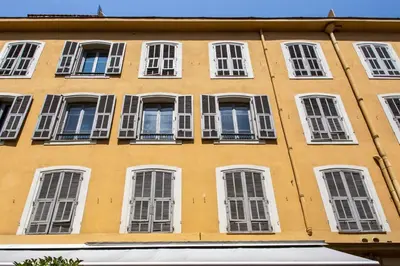 a tall yellow building with white windows at Studio Francilia - Welkeys in Nice