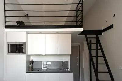 a loft kitchen with white cabinets and a ladder at Studio Francilia - Welkeys in Nice