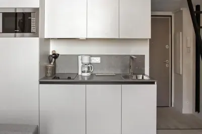 a white kitchen with white cabinets and a sink at Studio Francilia - Welkeys in Nice