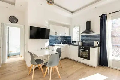 a kitchen with white cabinets and a table and chairs at Renovated Apartment Near the Beach in Nice