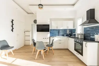 a kitchen with white cabinets and blue tiles at Renovated Apartment Near the Beach in Nice