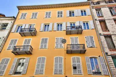 a yellow building with balconies and a clock on it at Very nice 2p with all comfort, city center Ac/wifi in Nice