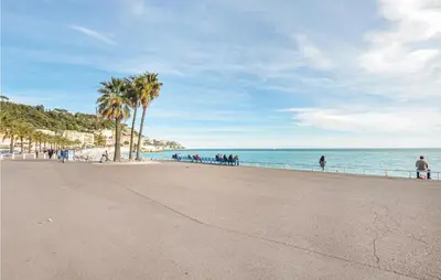a beach with a fence and palm trees and the ocean at Nice Apartment In Nice With Wifi in Nice