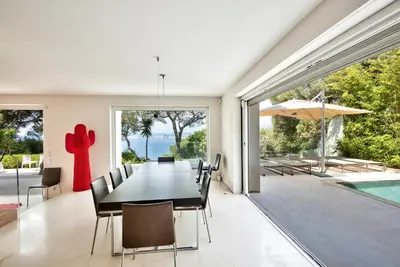 a dining room with a table and chairs and a pool at Villa Mont Boron, vue mer exceptionnelle in Nice