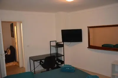 a living room with a table and a television on a wall at 4 pièces à Nice - 20 min de la plage in Nice