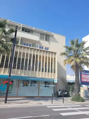 a building with palm trees in front of a street at Nice & Les Cypres in Nice