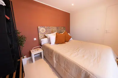 a small bedroom with a bed with orange walls at Lumineux, tout confort, Wifi & Terrace & Parking in Saint-Laurent-du-Var