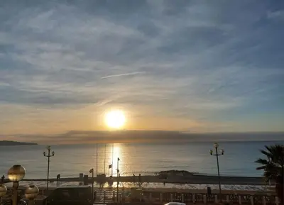 a sunset over the ocean with the sun in the sky at Nice Promenade des Anglais Vue Mer in Nice