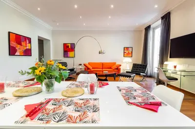 a living room with a white table and an orange couch at Market Square 2 bedrooms 2 baths AC private garage in Beaulieu-sur-Mer