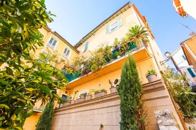 a yellow house with plants on a fence at LE MAY AP4338 By Riviera Holiday Homes in Villefranche-sur-Mer